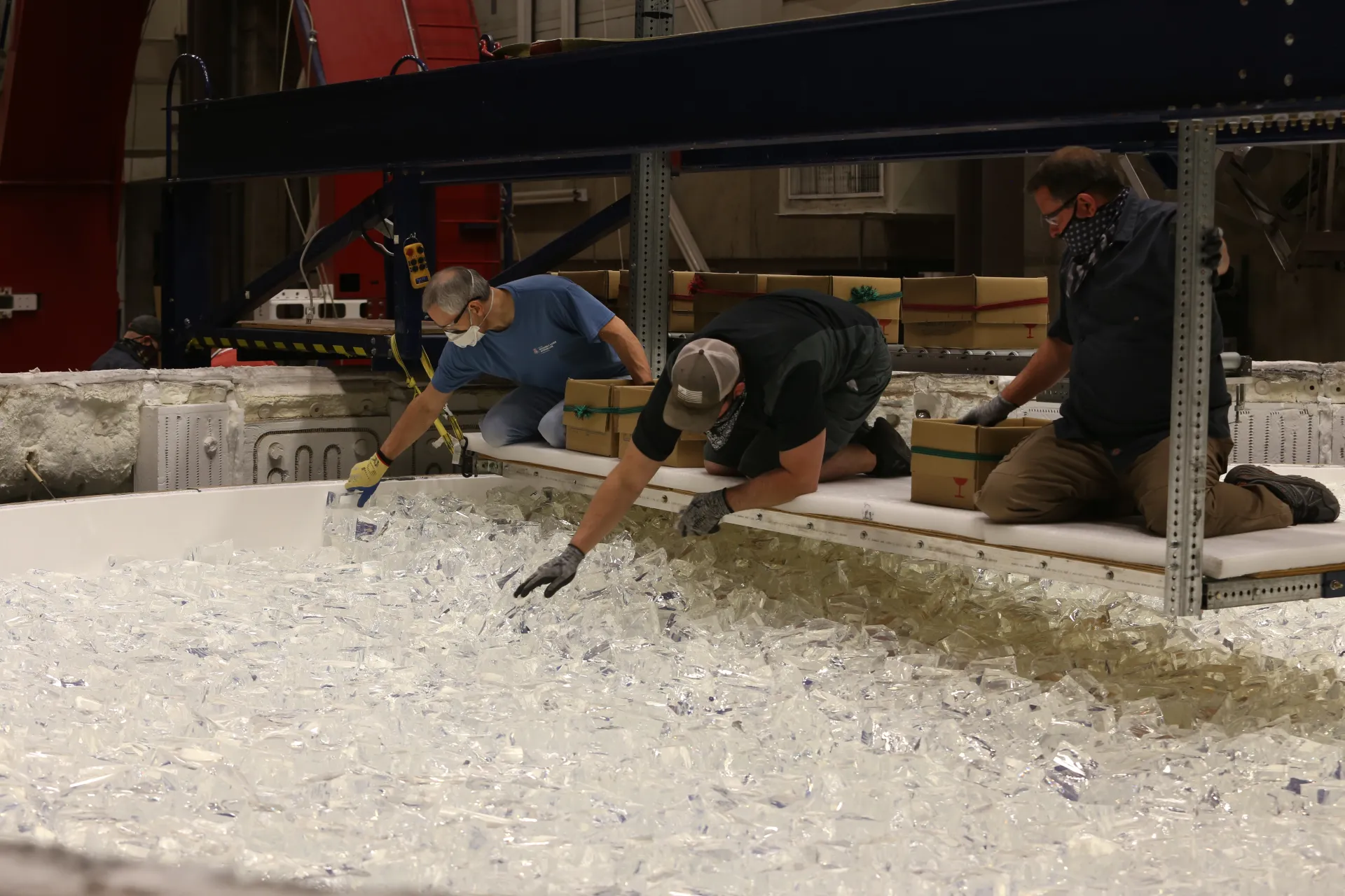 Engineers at the Richard F. Caris Mirror Lab hand-load chunks of glass into the mold. Almost 20 tons of glass are added this way before the lid will be closed and the furnace fired up to melt the glass.